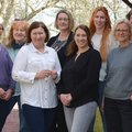 Acht Frauen stehen draußen zusammen als Gruppe.