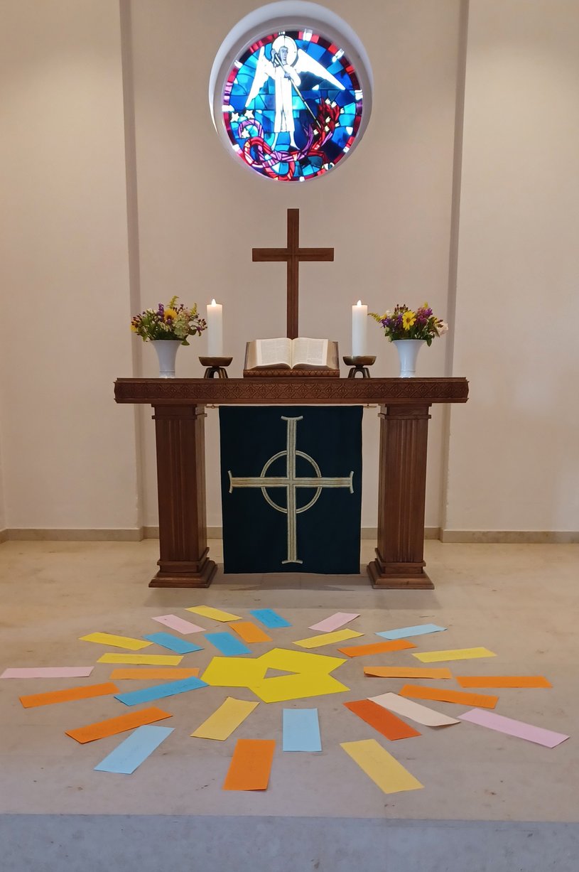 Altar und Fenster der St. Michaeliskirche mit einer aus Papierstreifen gebildeten Sonne auf dem Boden vor dem Altar